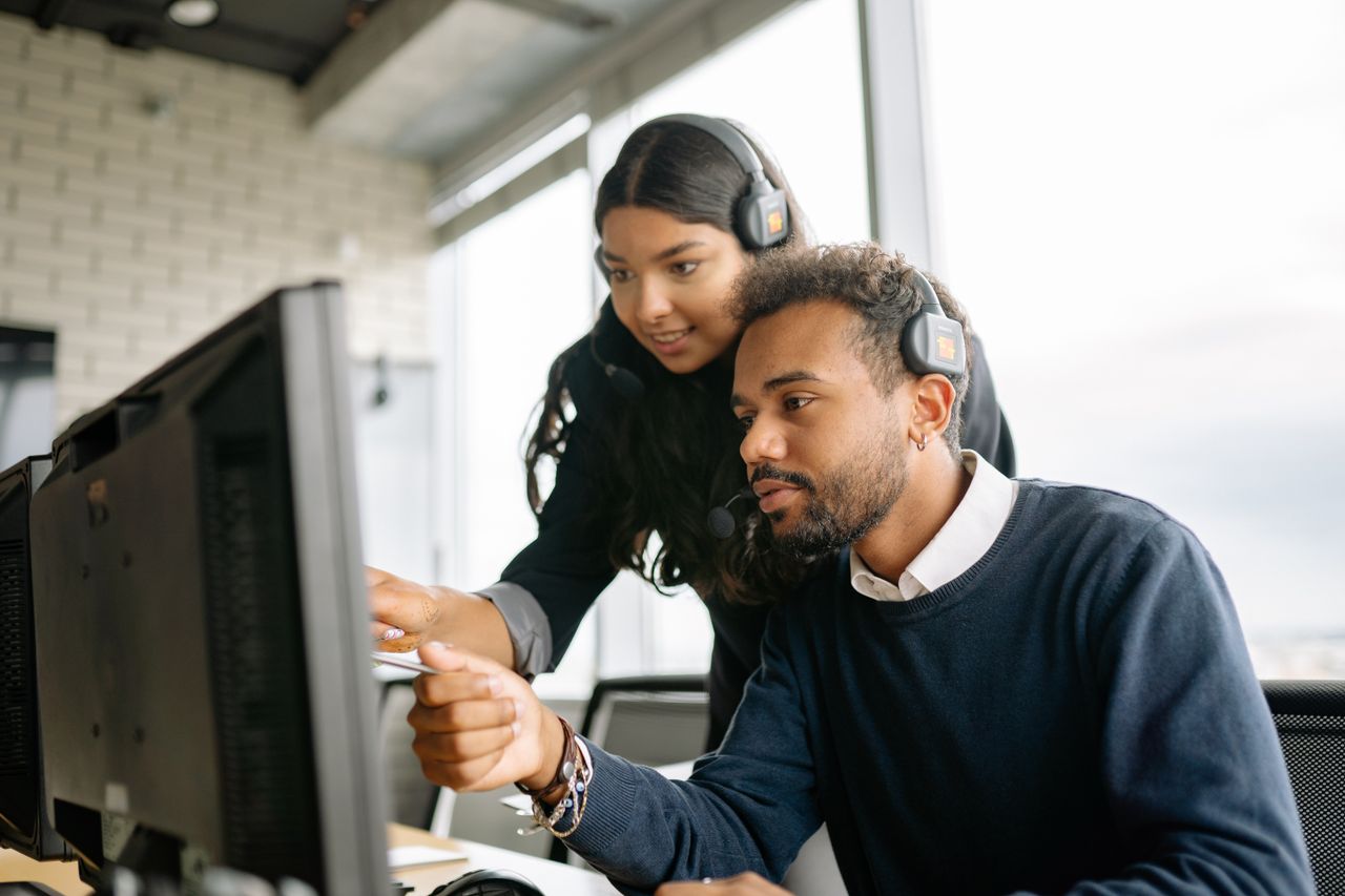 service-02 Two call center employees working together with headsets in a modern office setting.